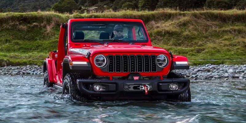 a red 2024 jeep wrangler driving through a body of water