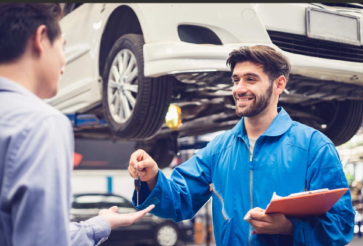 Automotive technician handing car keys to a customer after vehicle service or repair.