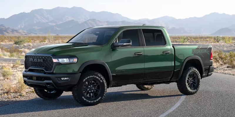 Green Ram pickup truck parked on a road with mountains in the background.